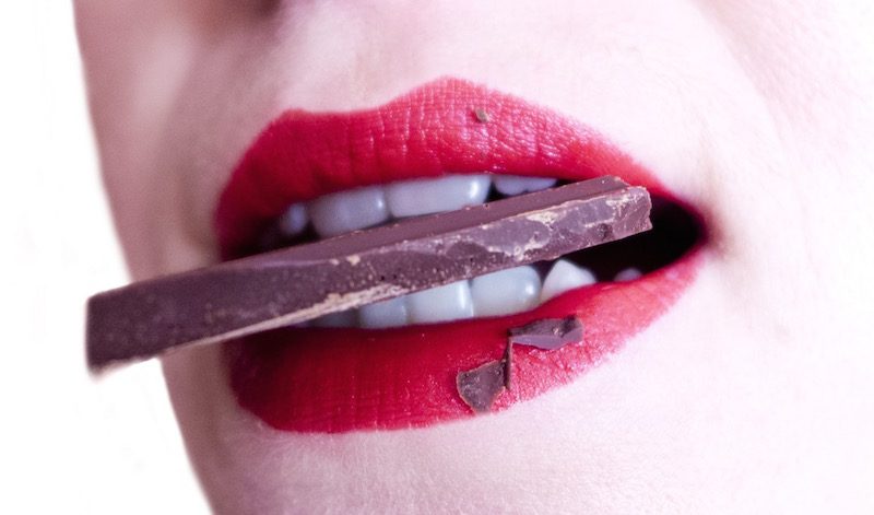 Smiling woman eating chocolate