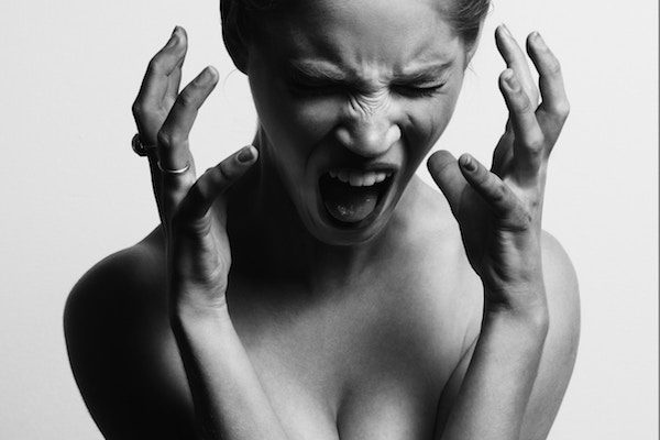 Woman screaming in pain with her hands raised.