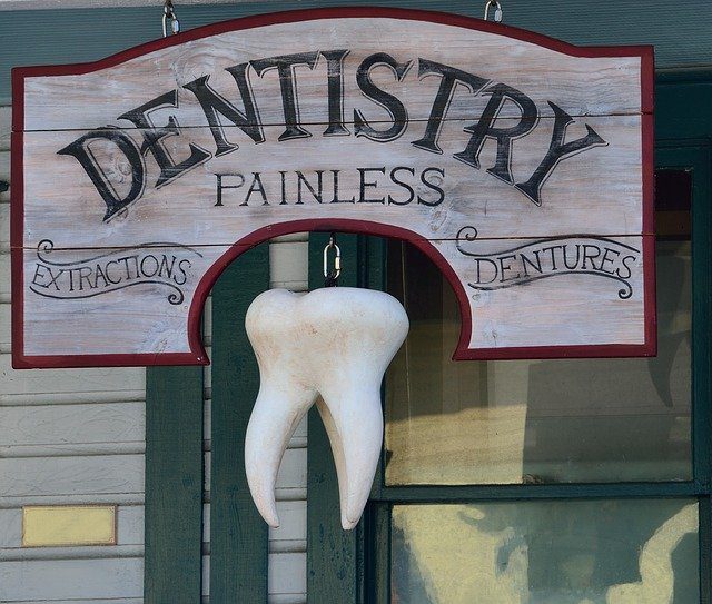 Old fashioned sign with an image of a large molar that reads - Dentistry, Painless, Extractions, Dentures.